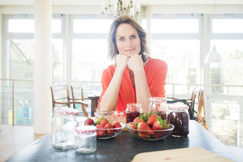 Porträt einer Frau mit selbstgemachter Erdbeermarmelade zu Hause, lizenzfreies Stockfoto