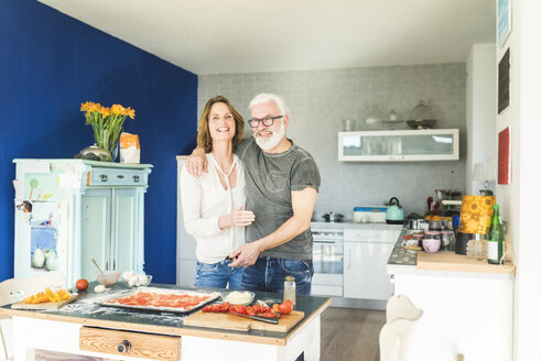 Happy mature couple embracing in kitchen at home - MOEF00940