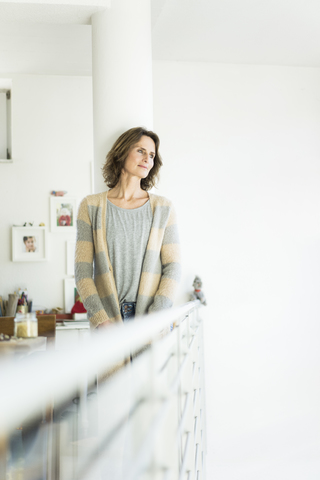 Woman leaning against a column at home stock photo