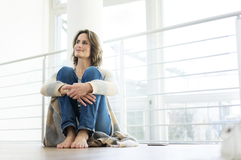 Relaxed woman sitting on the floor at home stock photo