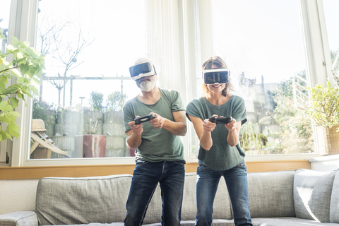 Reifes Paar in Kiving-Zimmer zu Hause mit VR-Brille spielen Videospiel, lizenzfreies Stockfoto