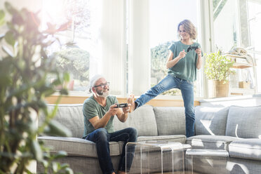 Glückliches reifes Paar auf der Couch zu Hause spielen Videospiel - MOEF00971