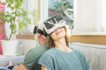 Älteres Paar sitzt zu Hause auf der Couch und trägt eine VR-Brille - MOEF00972