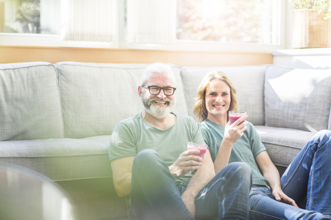 Glückliches reifes Paar mit gesunden Getränken im Wohnzimmer zu Hause, lizenzfreies Stockfoto