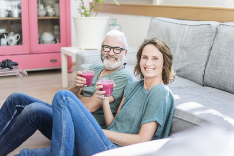 Glückliches reifes Paar mit gesunden Getränken im Wohnzimmer zu Hause, lizenzfreies Stockfoto
