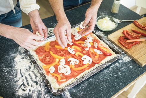 Nahaufnahme eines Paares bei der Zubereitung einer Pizza in der Küche zu Hause - MOEF00985