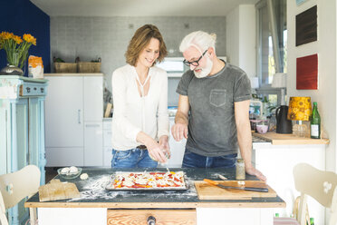 Älteres Paar bereitet eine Pizza in der Küche zu Hause vor - MOEF00987