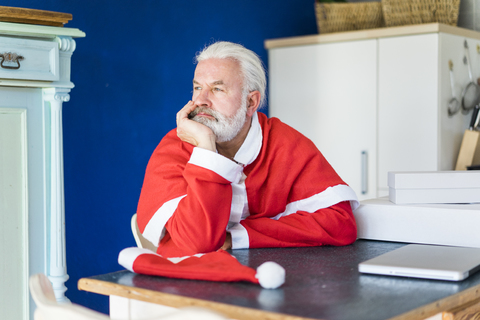 Bärtiger reifer Mann im Weihnachtsmannkostüm mit Blick in die Ferne, lizenzfreies Stockfoto