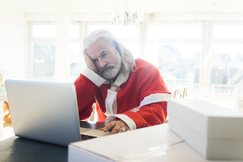 Frustrated Santa using laptop at home stock photo