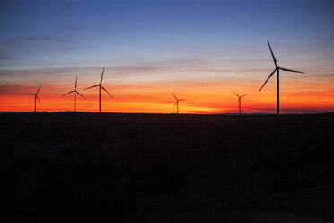 Silhouette windmills on field against cloudy sky at dusk - CAVF24916