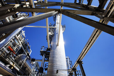 Low angle view of pipelines and chimney at power station against clear sky - CAVF24984