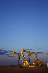 Ölpumpen auf einem Feld vor blauem Himmel in der Abenddämmerung - CAVF24990