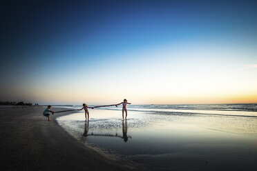 Geschwister spielen am Strand gegen den klaren Himmel bei Sonnenuntergang - CAVF25053