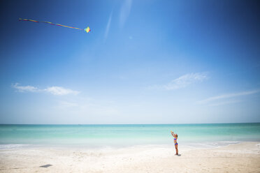 Mädchen fliegt Drachen am Strand gegen Meer und Himmel - CAVF25060