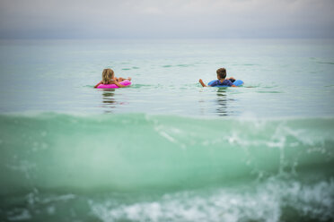 Geschwister in aufblasbaren Ringen schwimmen auf dem Meer - CAVF25063