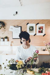 Florist working at table in flower shop - CAVF25096