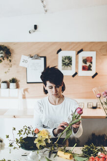 Floristin bei der Arbeit am Tisch im Blumenladen - CAVF25096