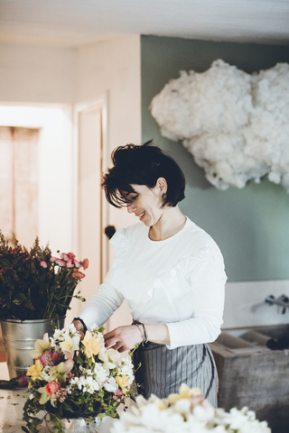 Smiling florist arranging flowers at store stock photo