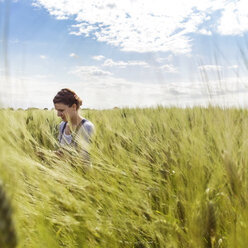 Frau in kultiviertem Weizenfeld vor klarem Himmel - CAVF25115