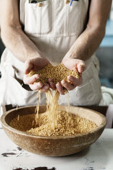 Mid section of farmer holding wheat in cupped hands at farm - CAVF25117