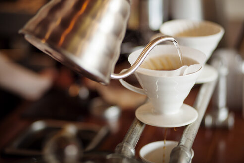 Wasser wird aus dem Wasserkocher in den Kaffeefilter eines Cafés gegossen - CAVF25156