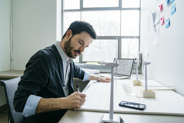 Geschäftsmann arbeitet im Büro an Modellen für Windkraftanlagen - CAVF25202