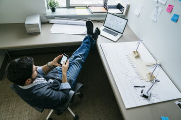 Blickwinkel eines Geschäftsmannes, der ein Smartphone benutzt, während er im Büro sitzt - CAVF25205