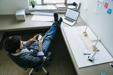 High angle view of businessman using smart phone while sitting in office - CAVF25205