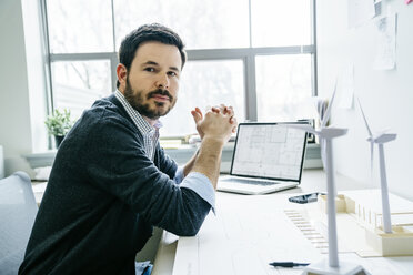 Porträt eines Geschäftsmannes mit verschränkten Händen am Schreibtisch sitzend im Büro - CAVF25208