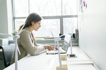 Side view of businesswoman using laptop computer while working in office - CAVF25218