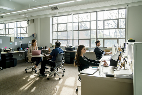 Geschäftsleute, die am Schreibtisch im Büro sitzen und diskutieren, lizenzfreies Stockfoto