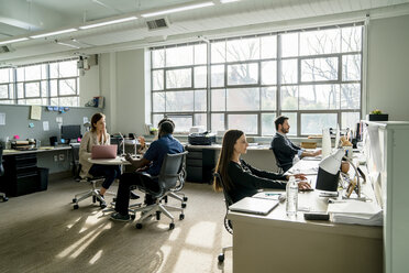 Geschäftsleute, die am Schreibtisch im Büro sitzen und diskutieren - CAVF25224