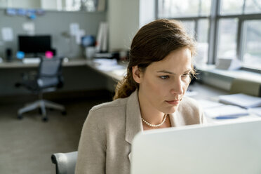 Geschäftsfrau, die einen Desktop-Computer benutzt, während sie im Büro sitzt - CAVF25230