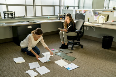 Geschäftsfrauen ordnen Dokumente auf dem Boden im Büro - CAVF25233