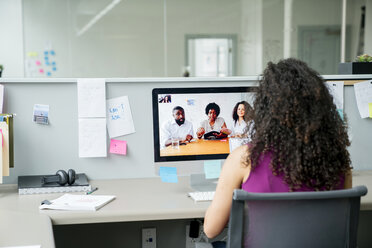 Rückansicht einer Geschäftsfrau bei einer Videokonferenz mit Kollegen über einen Desktop-Computer am Schreibtisch im Büro - CAVF25242