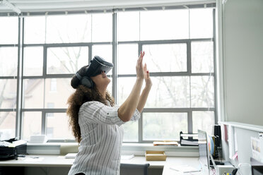 Businesswoman wearing virtual reality simulator in office - CAVF25248