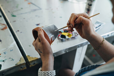 Cropped image of businesswoman painting terracotta pot - CAVF25277