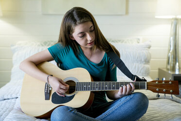 Teenager-Mädchen zupft Gitarre im Schlafzimmer - CAVF25321