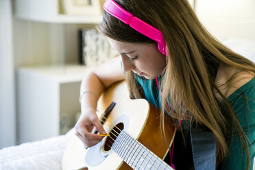 Teenager-Mädchen spielt Gitarre im Schlafzimmer - CAVF25327