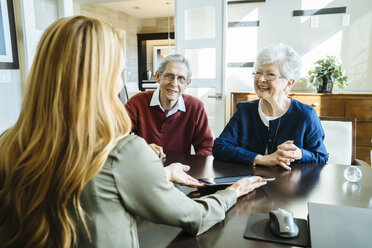 Female financial advisor explaining plan to senior couple on tablet computer in office - CAVF25354