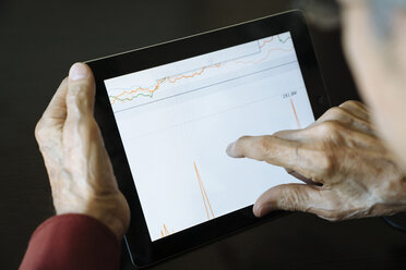 Ausgeschnittenes Bild eines älteren Mannes, der eine Grafik auf einem Tablet-Computer im Büro eines Finanzberaters analysiert - CAVF25370