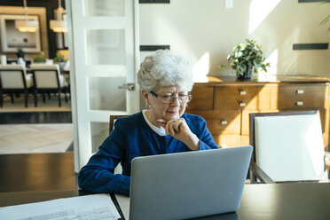 Ernste ältere Frau, die einen Laptop zu Hause benutzt - CAVF25374