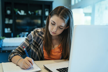 Teenage girl doing homework using laptop computer at home - CAVF25377