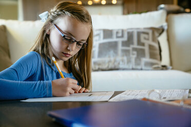 Serious girl doing homework at table - CAVF25381