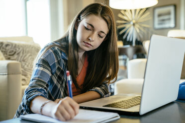 Seriöses Teenager-Mädchen, das zu Hause am Laptop Hausaufgaben macht - CAVF25382