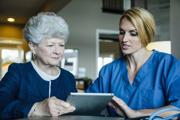 Hauspflegerin unterstützt ältere Frau bei der Benutzung eines Tablet-Computers - CAVF25387