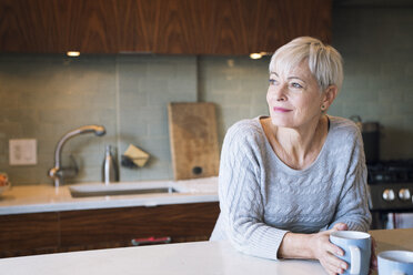 Thoughtful senior woman looking away while leaning on table - CAVF25420