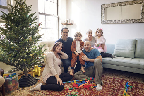Porträt einer lächelnden Familie am Weihnachtsbaum zu Hause - CAVF25441