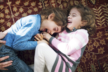 Overhead view of playful siblings lying on floor at home - CAVF25453