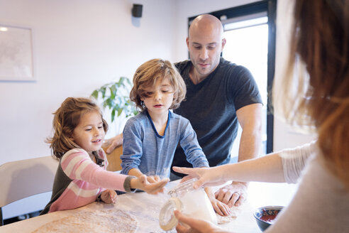 Eltern helfen Kindern beim Kneten von Teig am Tisch in der Küche - CAVF25457